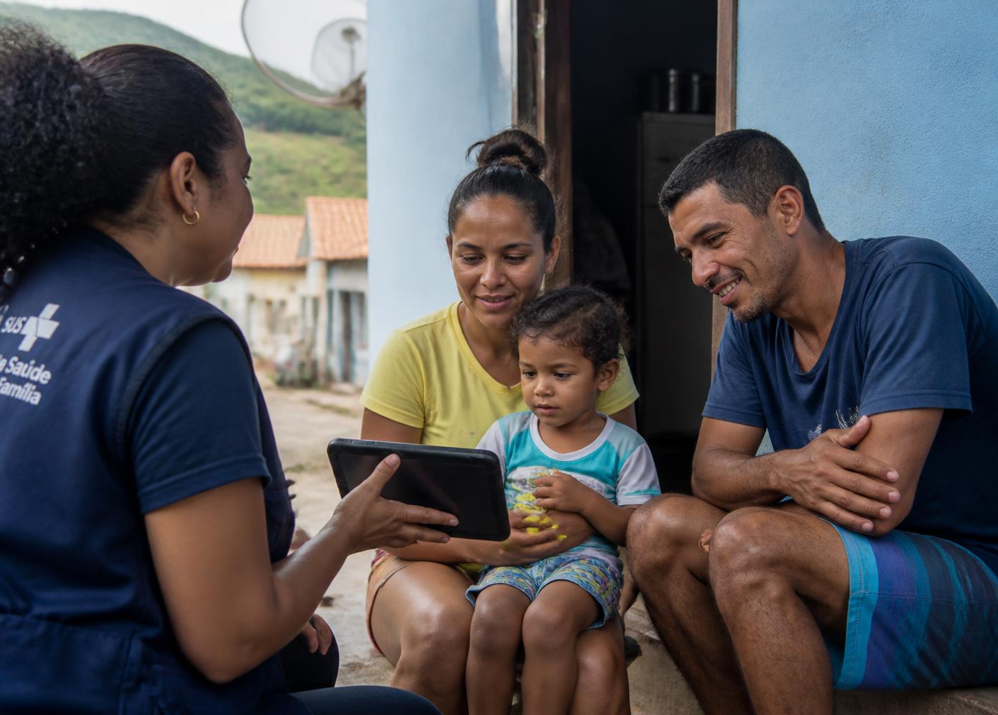 Agente comunitária de saúde em visita domiciliar registrando dados em tablet